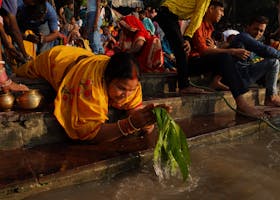 Hindu devotees perform traditional rituals on a Kolkata riverbank during a vibrant cultural festival.