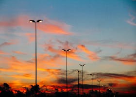 A vibrant sunset with silhouetted street lamps creating a serene skyline.