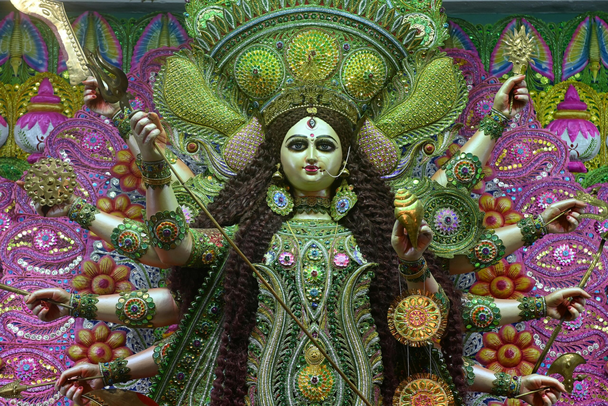 A vibrant sculpture of the Hindu goddess Durga adorned with jewels and holding weapons, symbolizing power and protection.