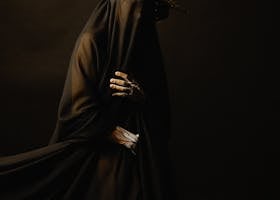 Mysterious figure draped in black with an elaborate crown. Eerie and elegant.