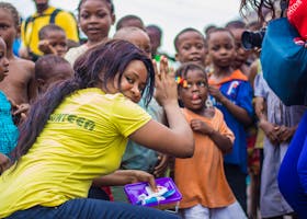 A vibrant scene of children and volunteers participating in an outdoor community outreach activity.