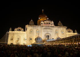 Spectacular view of a beautifully lit Gurudwara at night with a large gathering.