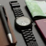 A neatly arranged flat lay depicting essential travel items such as a German passport, wristwatch, and euro bills on a desk. Inspector arrested passport fraud
