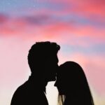 Silhouetted couple sharing an intimate moment against a colorful twilight sky. Rakesh Bedi- Sara Arjun