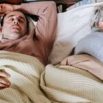 A middle-aged couple peacefully asleep in a cozy, well-lit bedroom setting. Sleeping Positions Married Couples