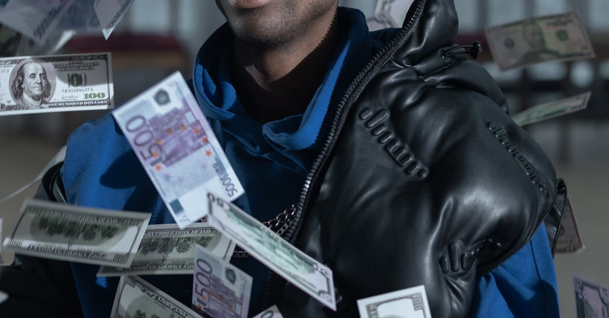A stylish man with a leather jacket and sunglasses surrounded by floating currency notes.